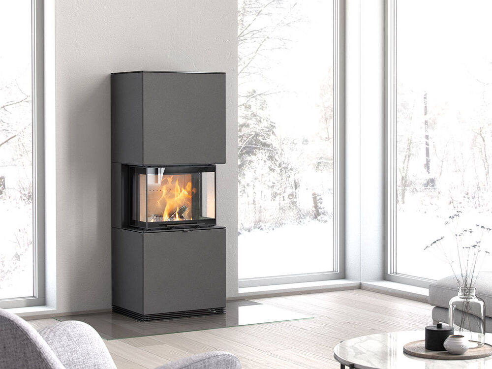 Moderner, schwarzer Kaminofen mit Glasfront, brennendem Feuer, steht in hellem Raum mit großen Fenstern und Holzboden.