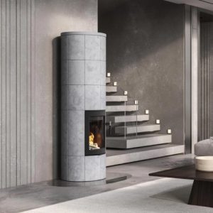 Moderner grauer Holzofen mit sichtbarer Flamme, daneben Holzstapel in Wandnische, darüber Wandregal mit Büchern und Dekoration.