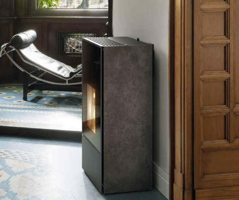 Moderner grauer Holzofen mit sichtbarer Flamme, daneben Holzstapel in Wandnische, darüber Wandregal mit Büchern und Dekoration.